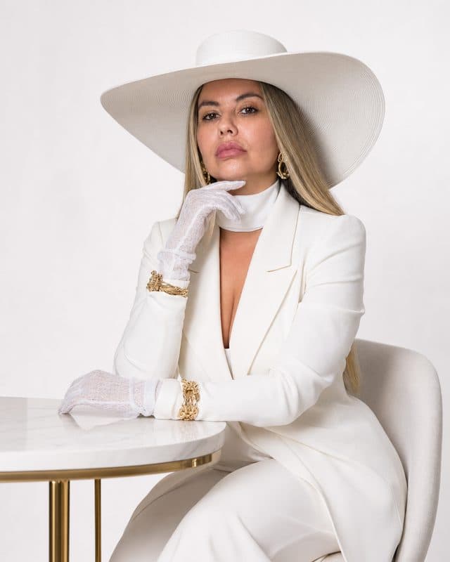 Ensaio feito no DanceIA — pose sentada com look branco e chapéu